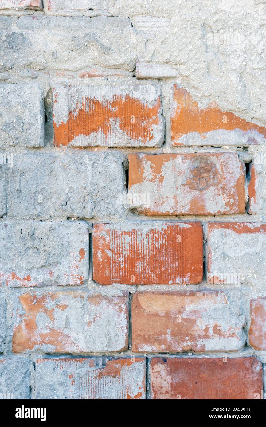 Eine Ziegelwand besteht aus einer Reihe von grauen und roten Ziegeln, die Verschleiß und Textur zeigen, die der Oberfläche Charakter verleiht. Die Kombination erzeugt eine Visua Stockfoto