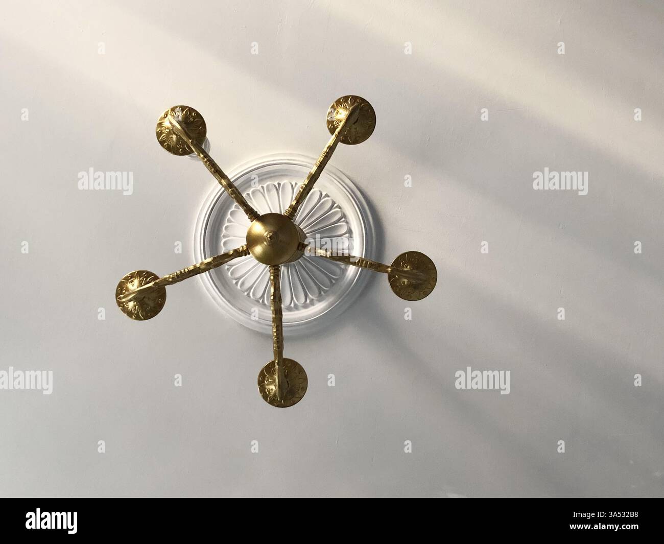 goldener Kronleuchter im klassischen Stil an der Decke mit Stuckrosette, innen Stockfoto