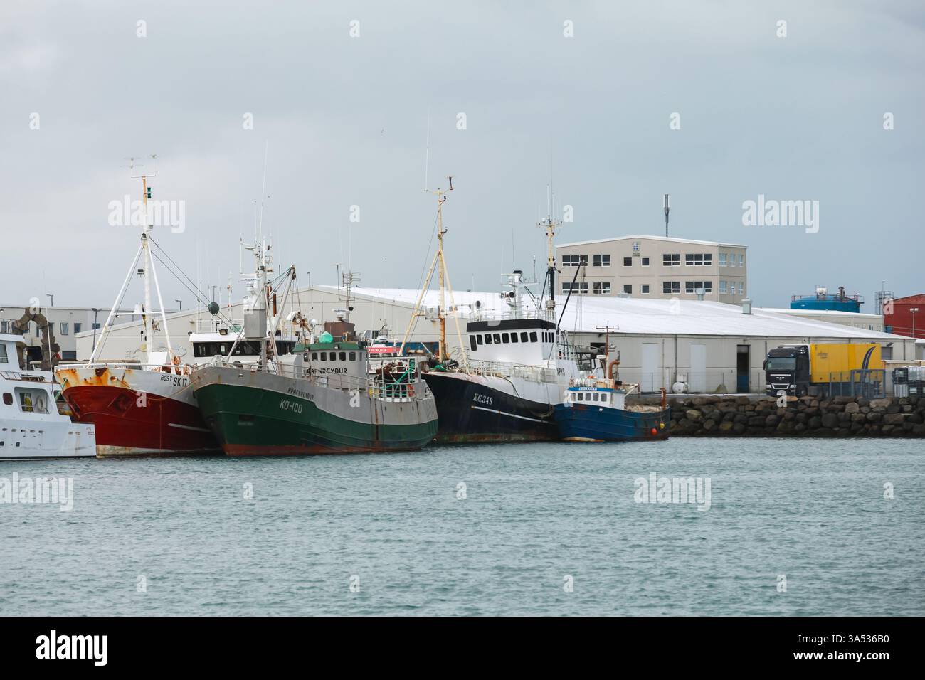 Reykjavik, Island - 4. April 2017: In einem Industriehafen liegen Fischerboote verschiedener Größe vor, im Hintergrund befinden sich Lagergebäude Stockfoto