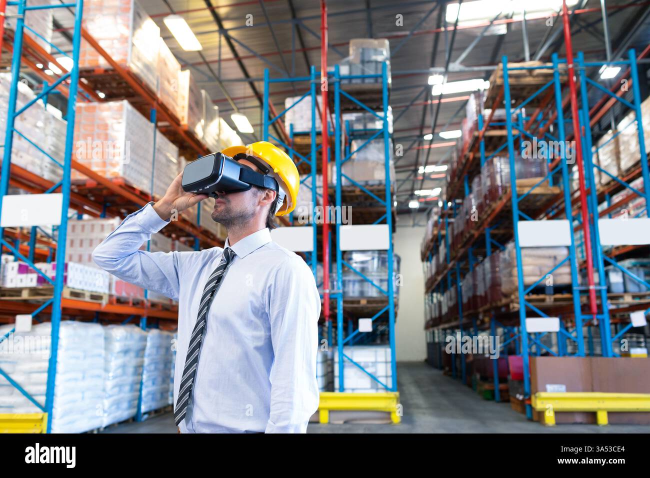 Lagerarbeiter mit VR-Headset und Schutzhelm erkunden virtuelle Logistik und Kopierraum Stockfoto