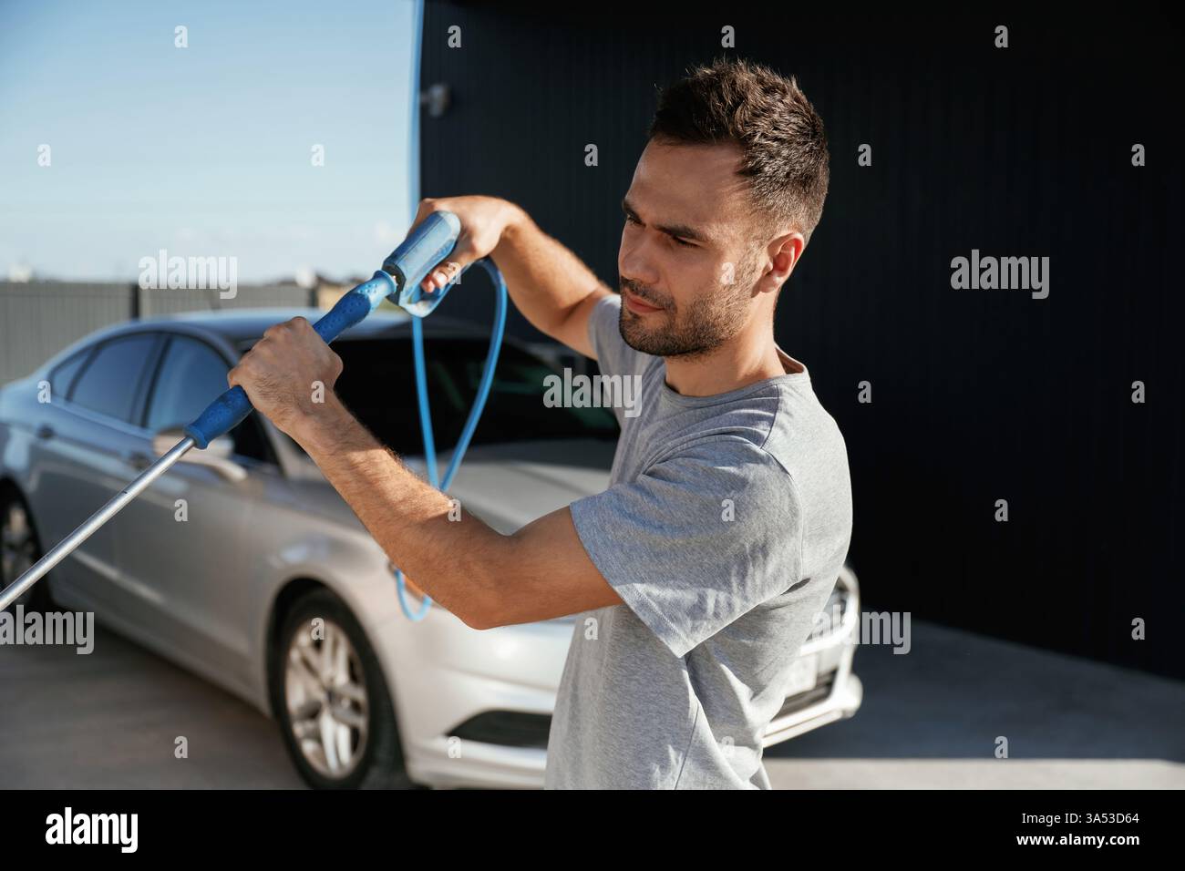 Bereit, das Auto zu waschen. Der Mann ist mit seinem Auto draußen. Stockfoto