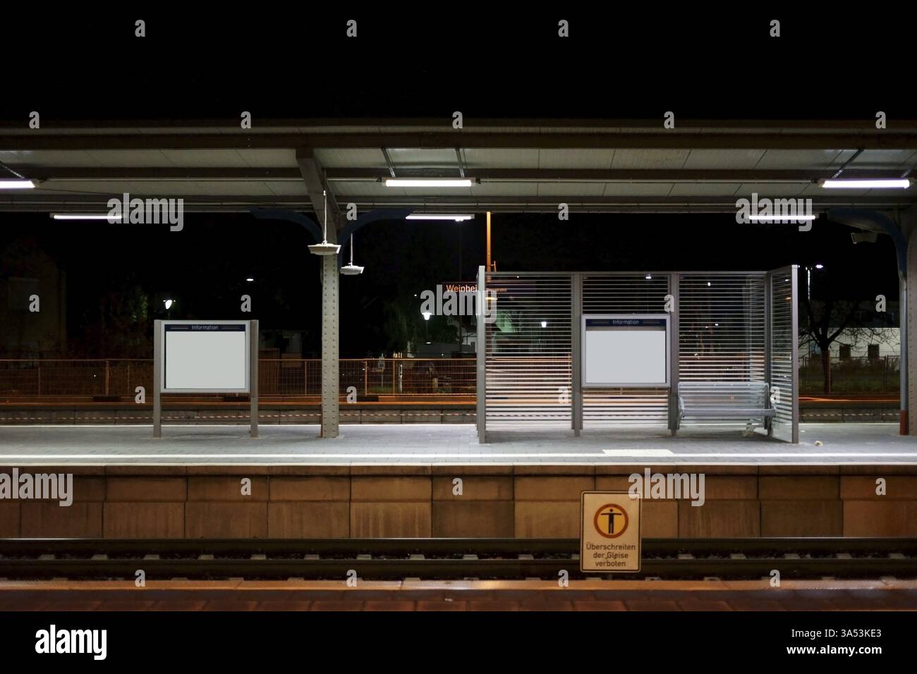 Der Bahnsteig des Bahnhofs Weinheim bei Nacht Sitzplatz entlang einer Glastrennwand Stockfoto