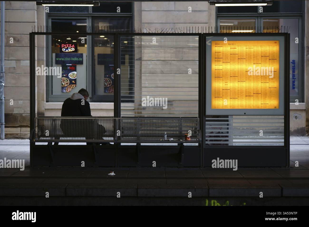 Mainz, Deutschland - 15. Oktober 2017: Ein Reisender sitzt am 15. Oktober 2017 in Mainz, Ger an einer Glaswand mit Zugfahrplänen an den Bahngleisen Stockfoto