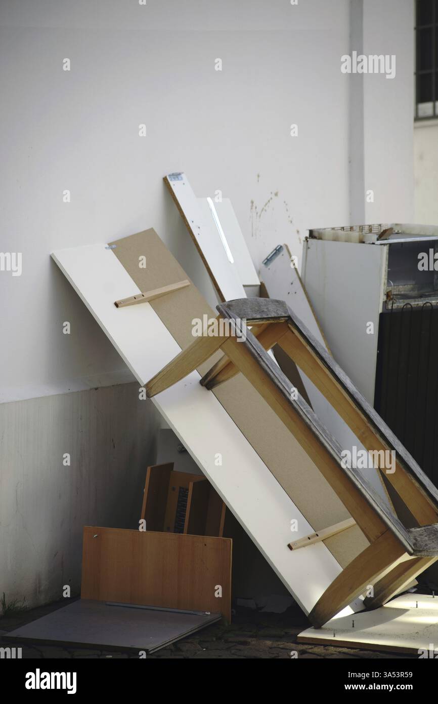 Sperrmüll wie Möbel- und Holzabfälle sowie ein Kühlschrank lehnen sich an eine Hauswand Stockfoto