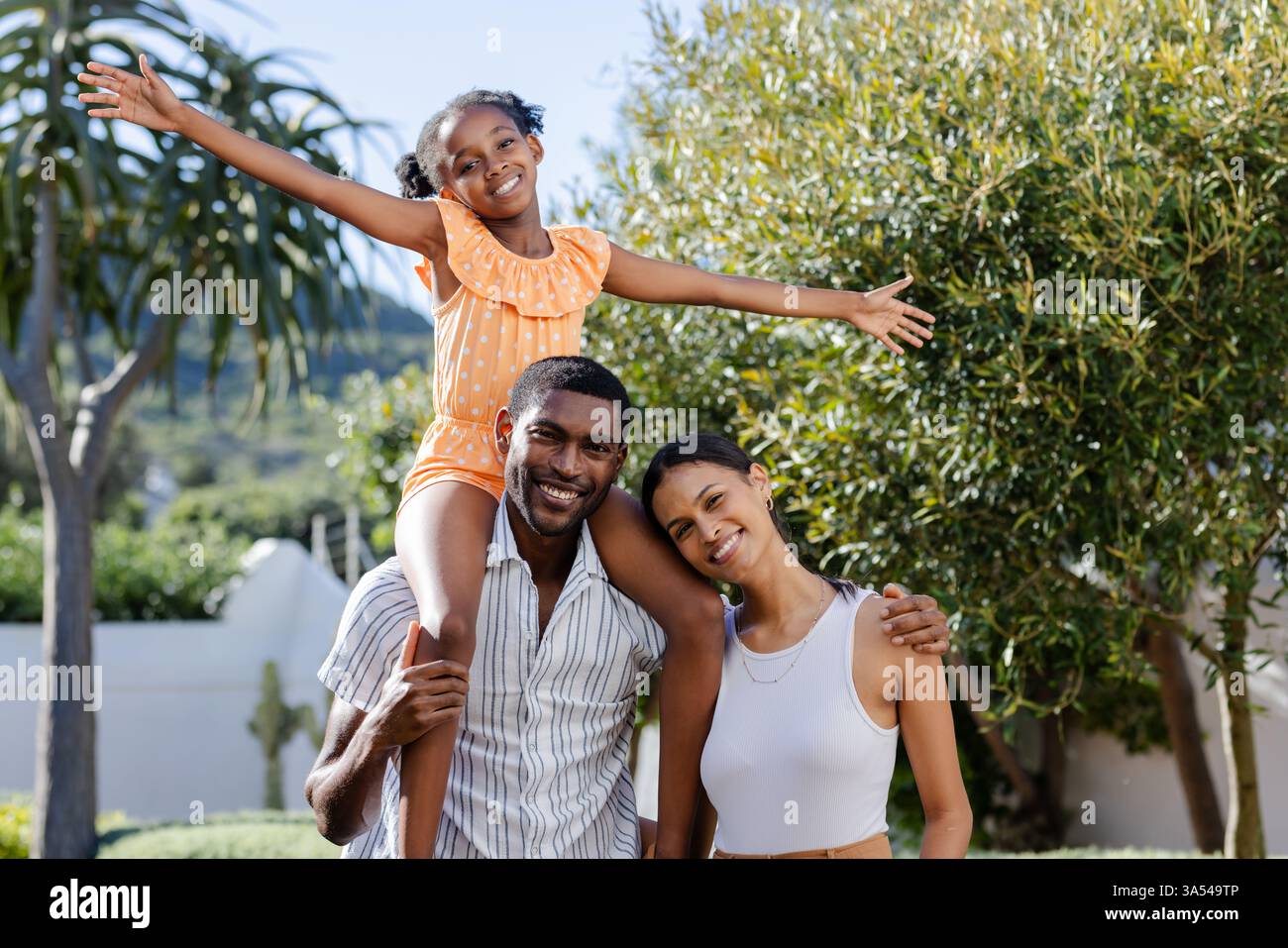 Lächelnde Familie, die Urlaub im Freien genießt, Tochter sitzt auf Vaters Schultern Stockfoto