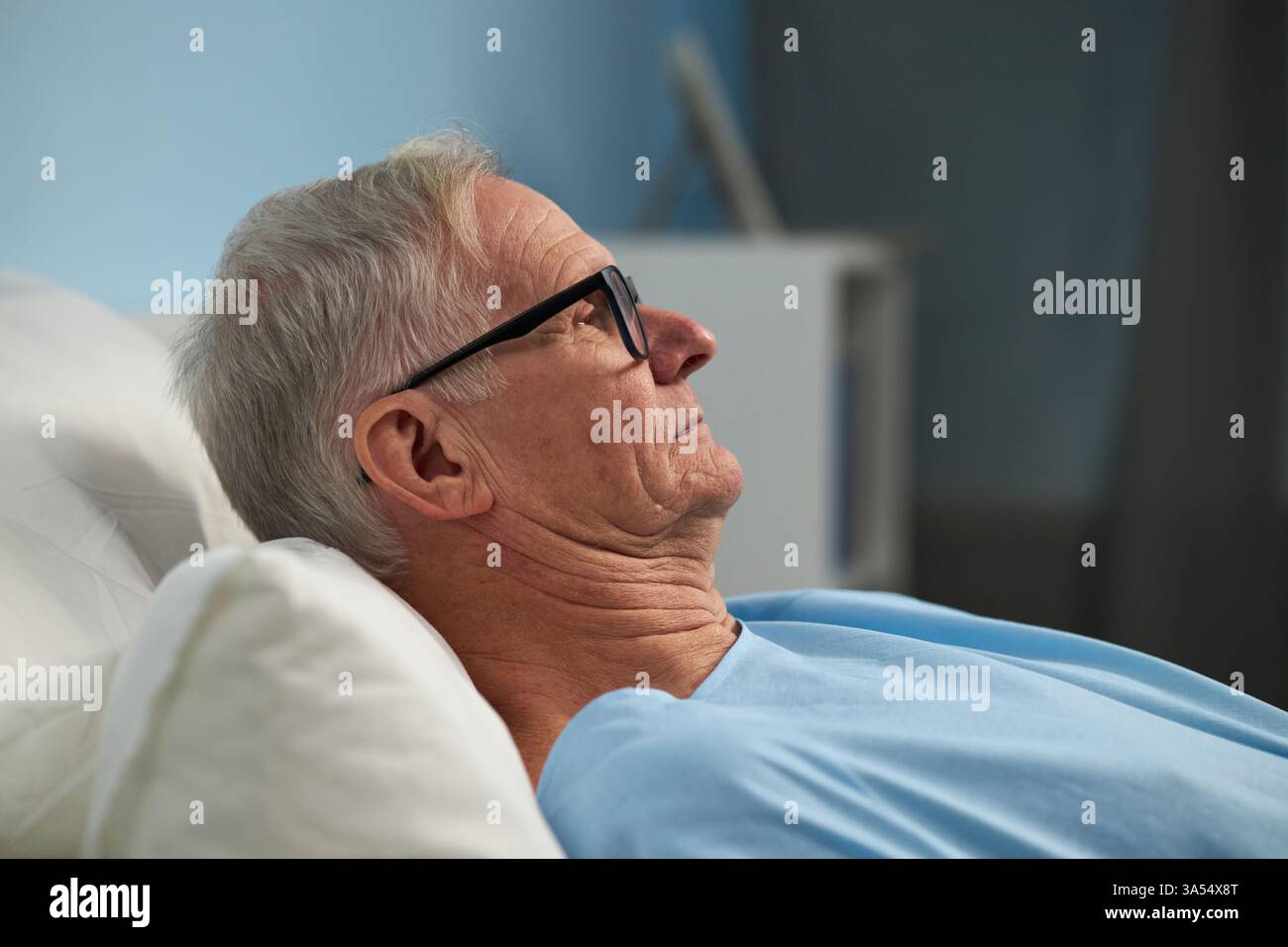 Ruhender älterer Mann in Krankenhausbettwäsche Stockfoto