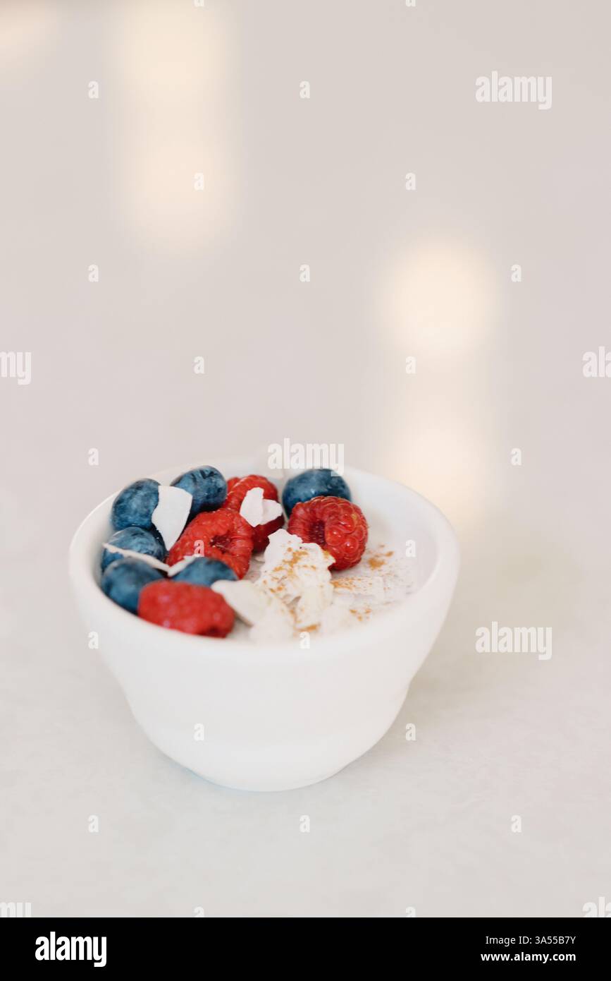 Eine minimalistische Schüssel Kokosjoghurt mit Beeren und Zimt Stockfoto