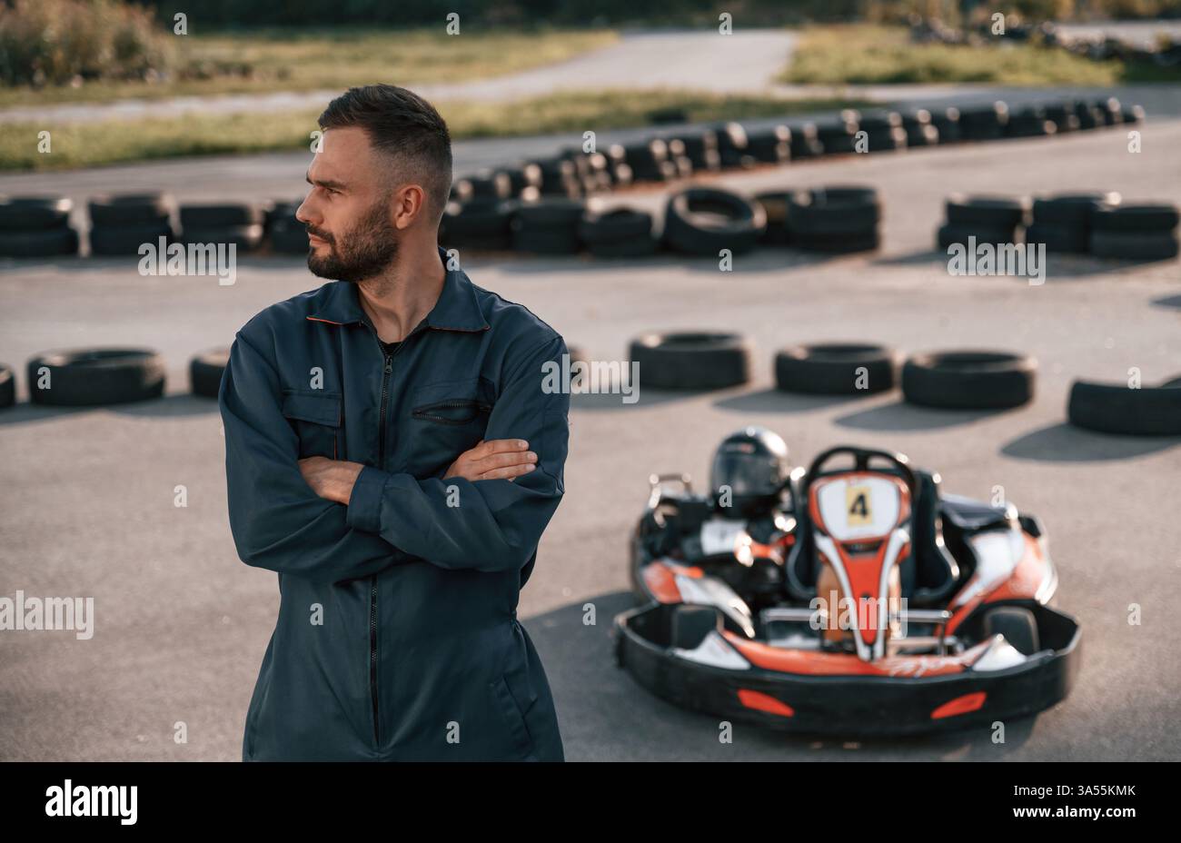 Stehend mit gekreuzten Armen. Der Mensch ist draußen, ein Kartrennen. Stockfoto