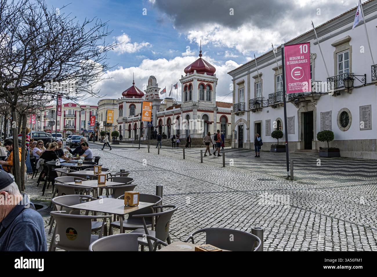 Das Zentrum von Loule, Faro, Portugal, mit Verwaltung und Marktaufstockung im Hintergrund. Das Restaurant liegt auf der Straßenseite des Bürgersteigs. Stockfoto