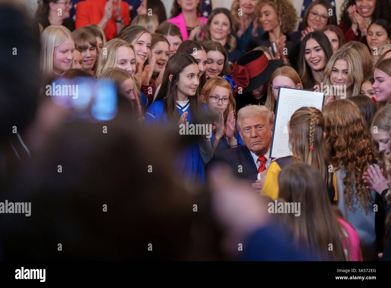 Präsident Donald Trump – umgeben von Frauen und Mädchen – hält eine Erklärung ab, als er am Mittwoch, den 5. Februar 2025, im östlichen Saal des Weißen Hauses eine „No Men in Women’s Sports“-Anordnung unterzeichnet. Stockfoto