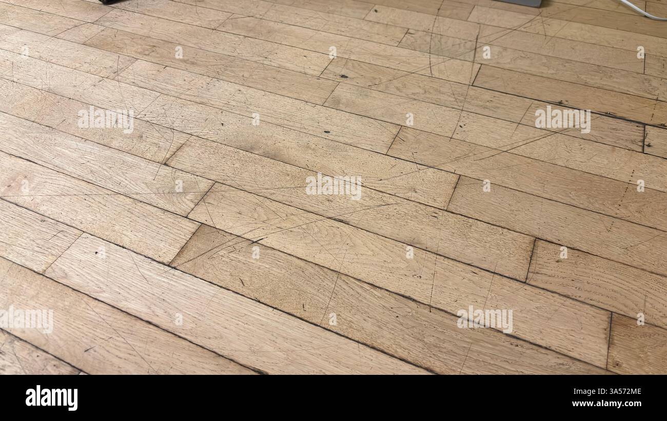 Nahaufnahme eines abgenutzten Holzbodens mit Schrammen und Markierungen. Gut genutzt. Der Boden ist kaputt und gefährlich - Smartphone-aufgenommenes Stockfoto