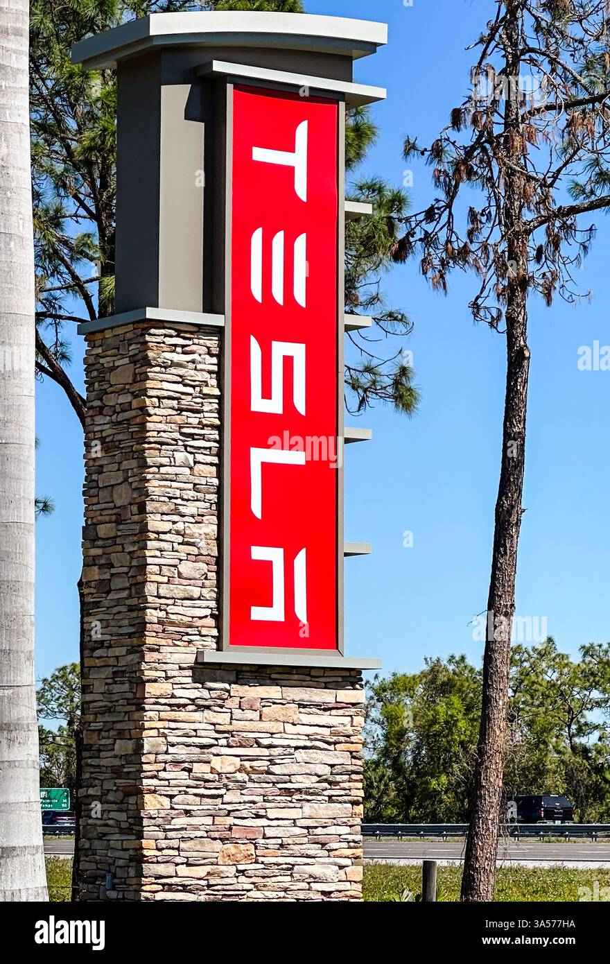 Schild Tesla Händlerbetrieb gegen blauem Himmel. Bradenton, FL, USA, 19. März 2025 - Smartphone-aufgenommenes Stockfoto