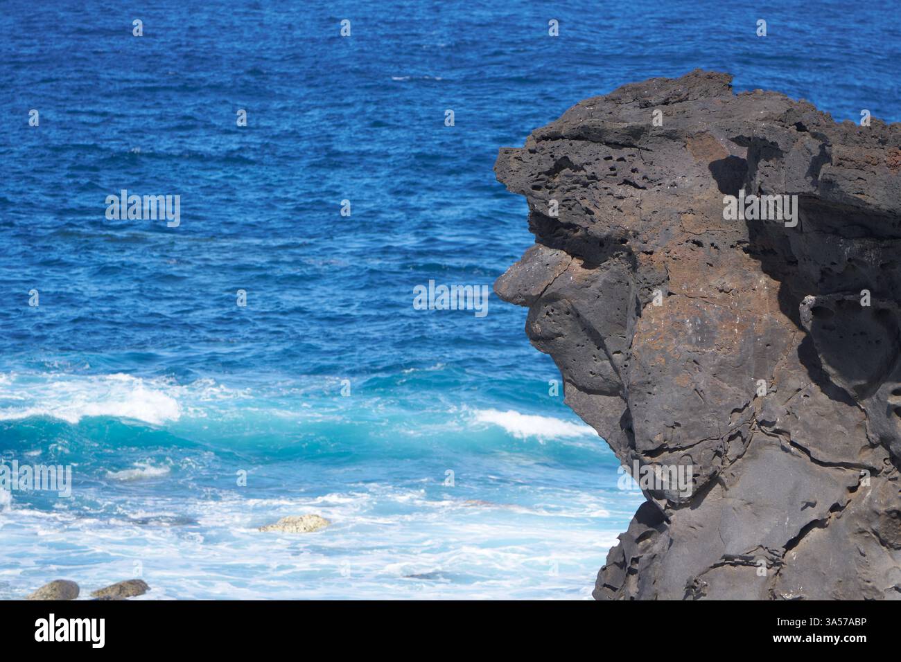 Felsen mit Gesicht vor dem blauen Meer Stockfoto