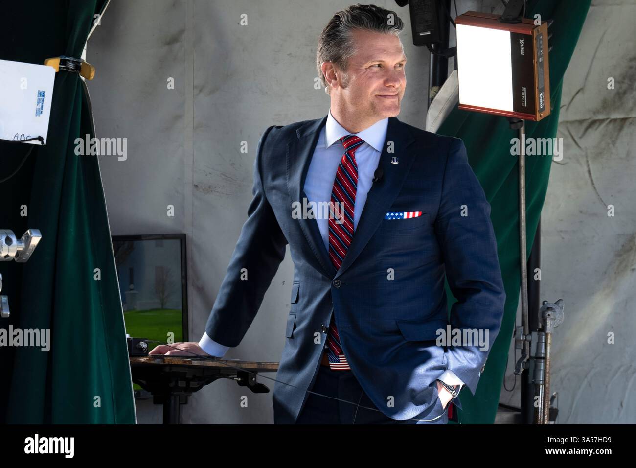 Wearing a U.S. flag themed pocket square and belt buckle, Defense Secretary Pete Hegseth waits for the start of a television interview outside the White House, Friday, March 21, 2025, in Washington. (AP Photo/Jacquelyn Martin) Stockfoto