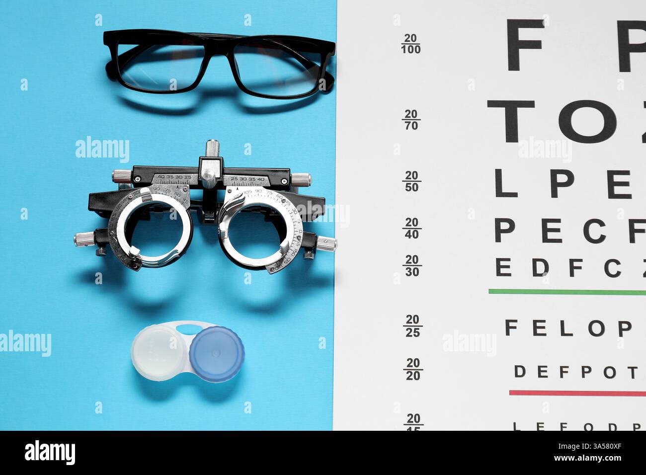 Brille, Testrahmen, Vision-Testkarte und Linsen auf hellblauem Hintergrund, flach gelegt Stockfoto