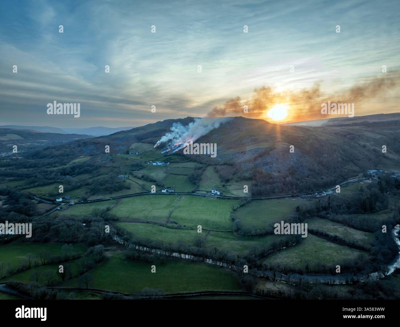 Ein Grasfeuer bei Sonnenuntergang auf einem Hügel in den Brecon Beacons in South Wales GB Stockfoto