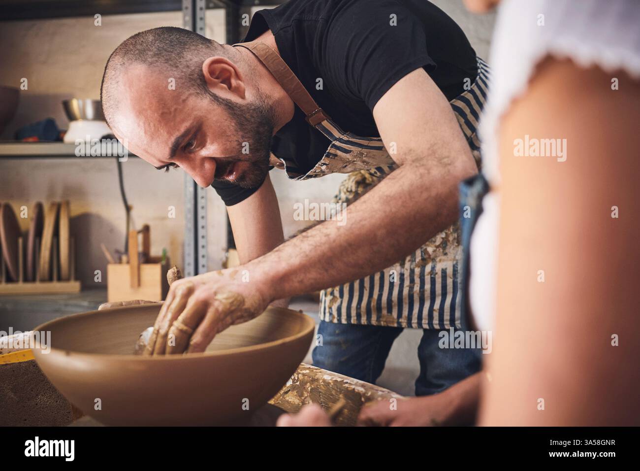 Menschen, Team und Töpferei im Tonstudio, arbeiten zusammen und schnitzen für keramisches Kunsthandwerk. Unterricht, Ausrüstung und Hilfestellung beim Unterricht in der Werkstatt Stockfoto