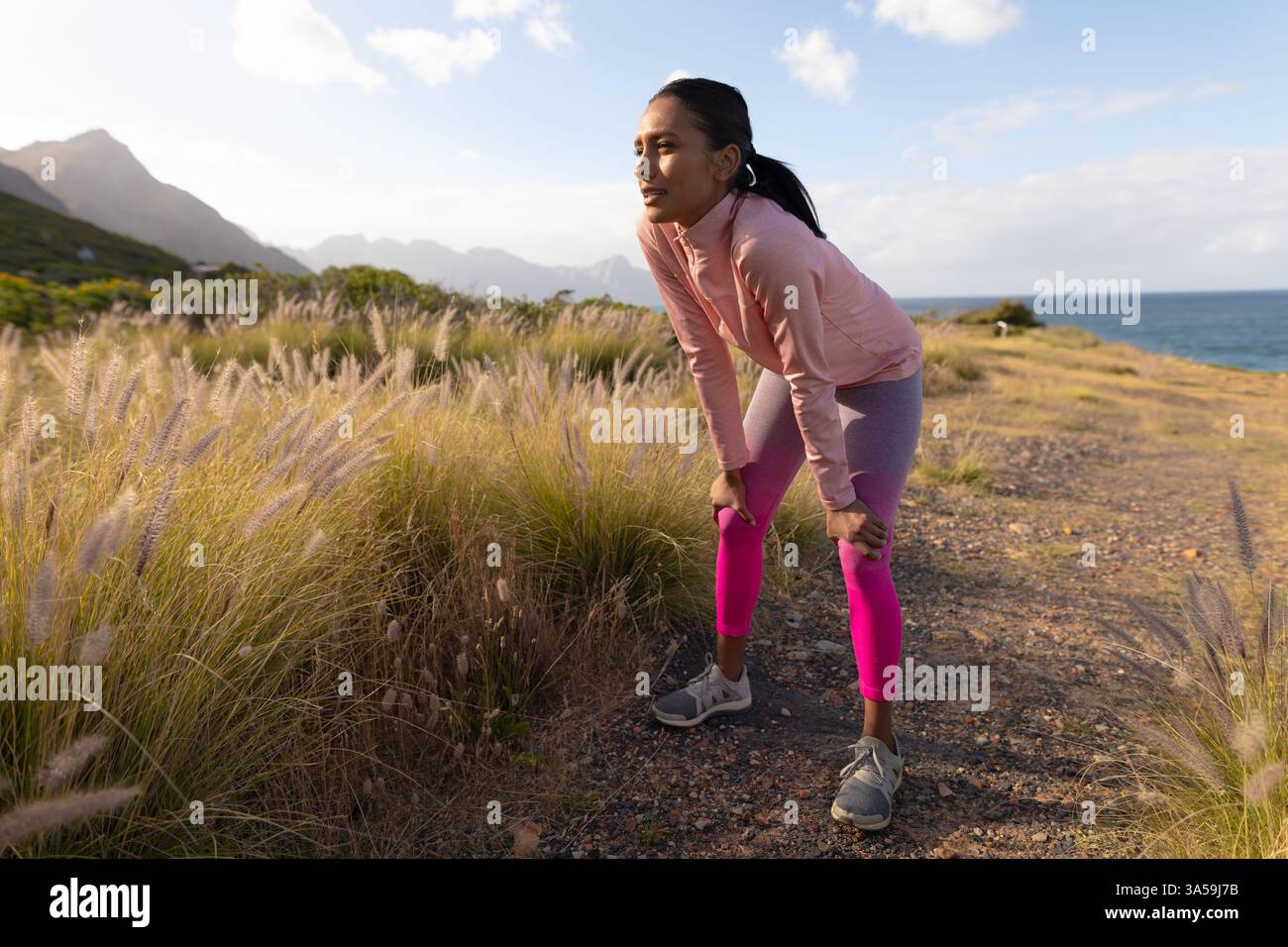 Frau, die sich ausruht, nachdem sie auf einem malerischen Pfad in der Nähe des Ozeans gelaufen ist, die Natur genießt, den Kopierraum Stockfoto