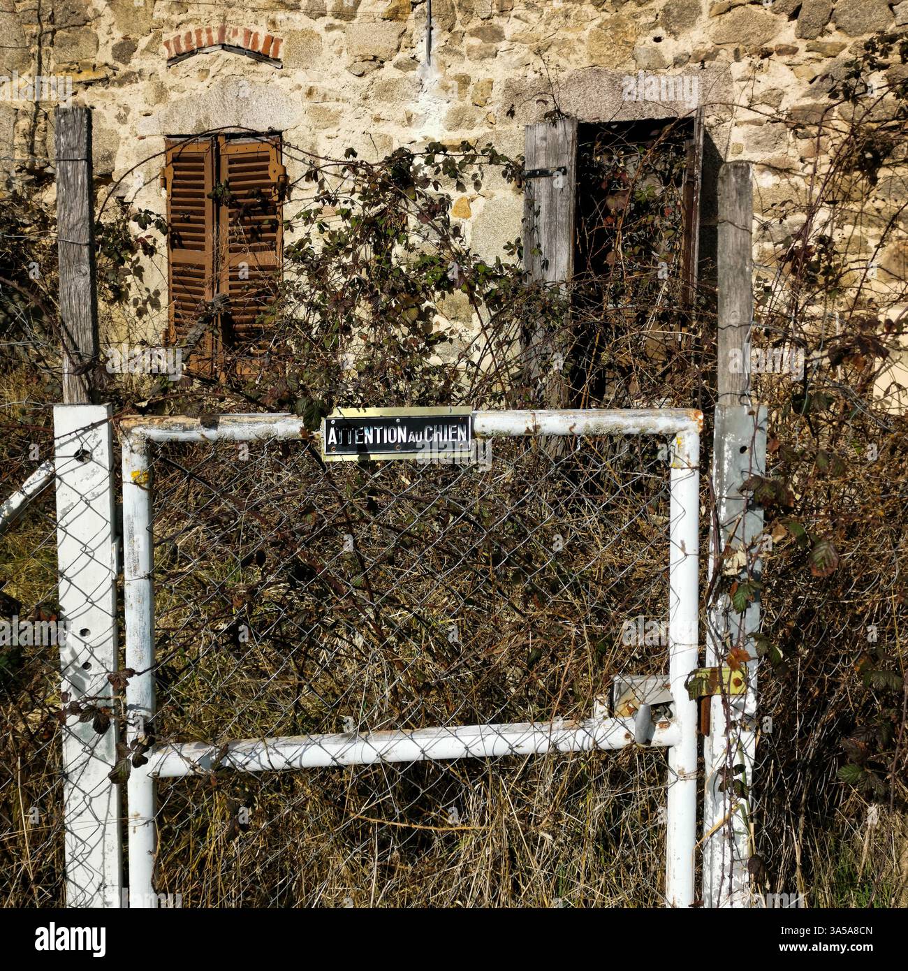 Altes verlassenes Haus in Puy de Dome mit einem Warnschild in einem ruhigen Dorf im Livradois Forez Park, Frankreich - Smartphone-aufgenommenes Stockfoto