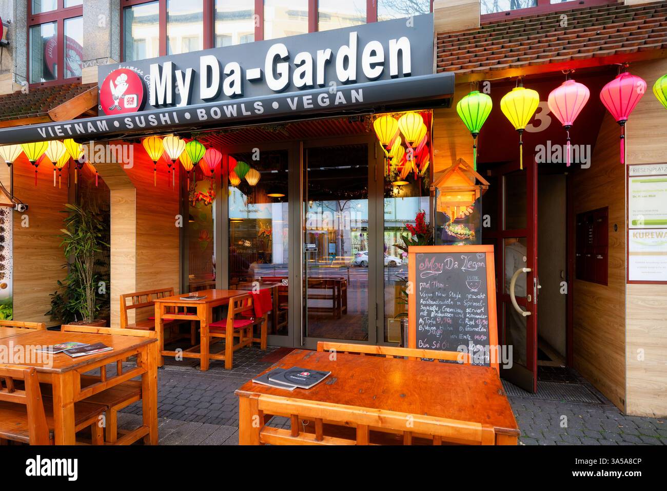 Köln, Deutschland 26. Dezember 2024: Tische, Stühle und leuchtende bunte Laternen am Eingang des vietnamesischen Restaurants My da-Garden im F Stockfoto