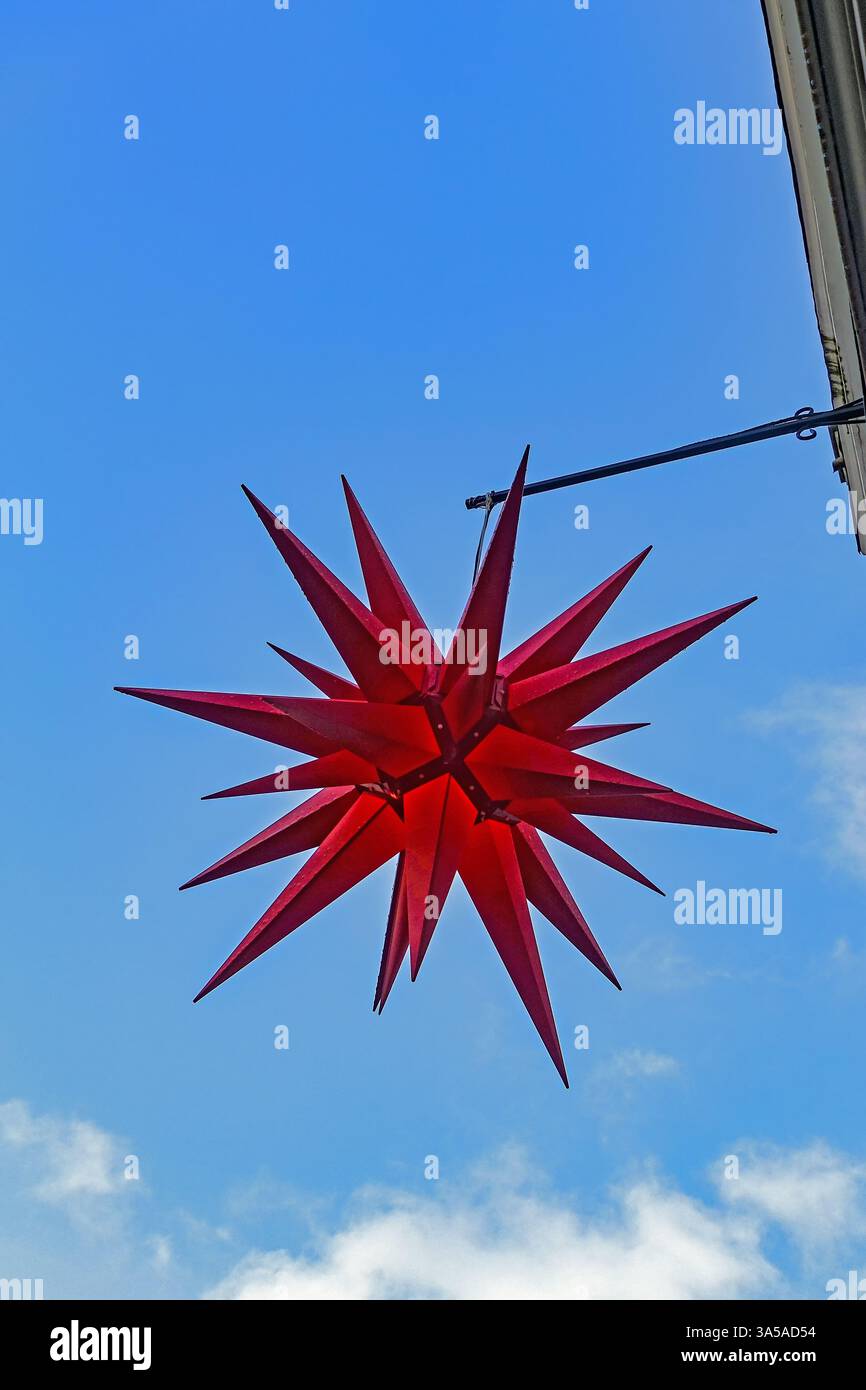 Roter Weihnachtsstern erstrahlt vor einem blauen Himmel Stockfoto