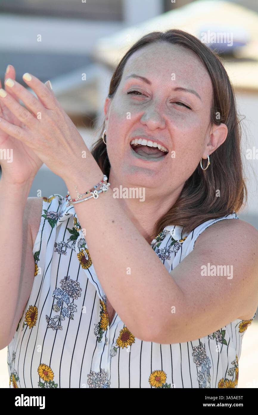 Ein offenes Bild einer entspannten Frau in lässiger Kleidung, mit einer Halskette verziert und natürlich lächelnd. Stockfoto