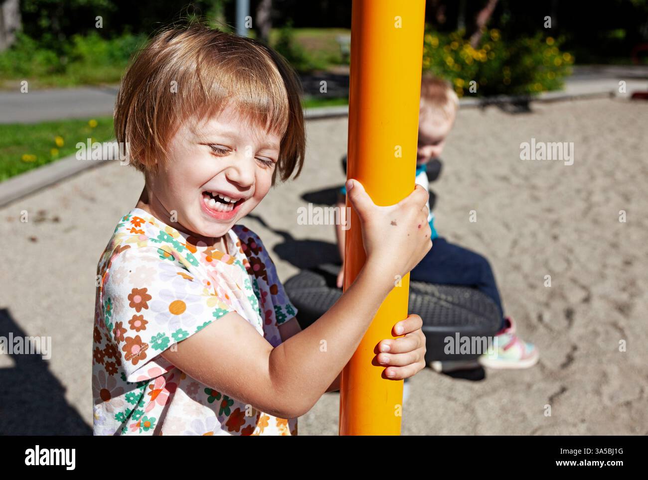 Ein fröhlicher Moment auf einem Spielplatz mit leuchtend orangefarbener Ausrüstung. Stockfoto