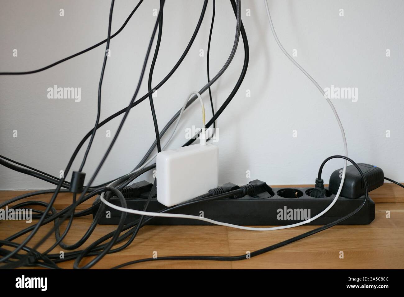 Viele Drähte in einer Steckdose am Arbeitsplatz. Chaos bei der Verkabelung. Konzept zur Frage der Raumeinsparung und Ästhetik. Stockfoto