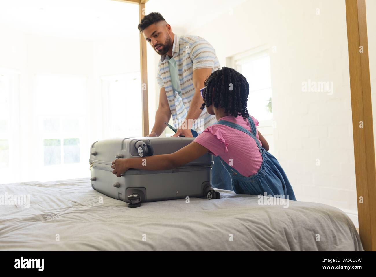 Vater und Tochter packen Koffer auf dem Bett, bereiten sich auf den Familienausflug vor Stockfoto