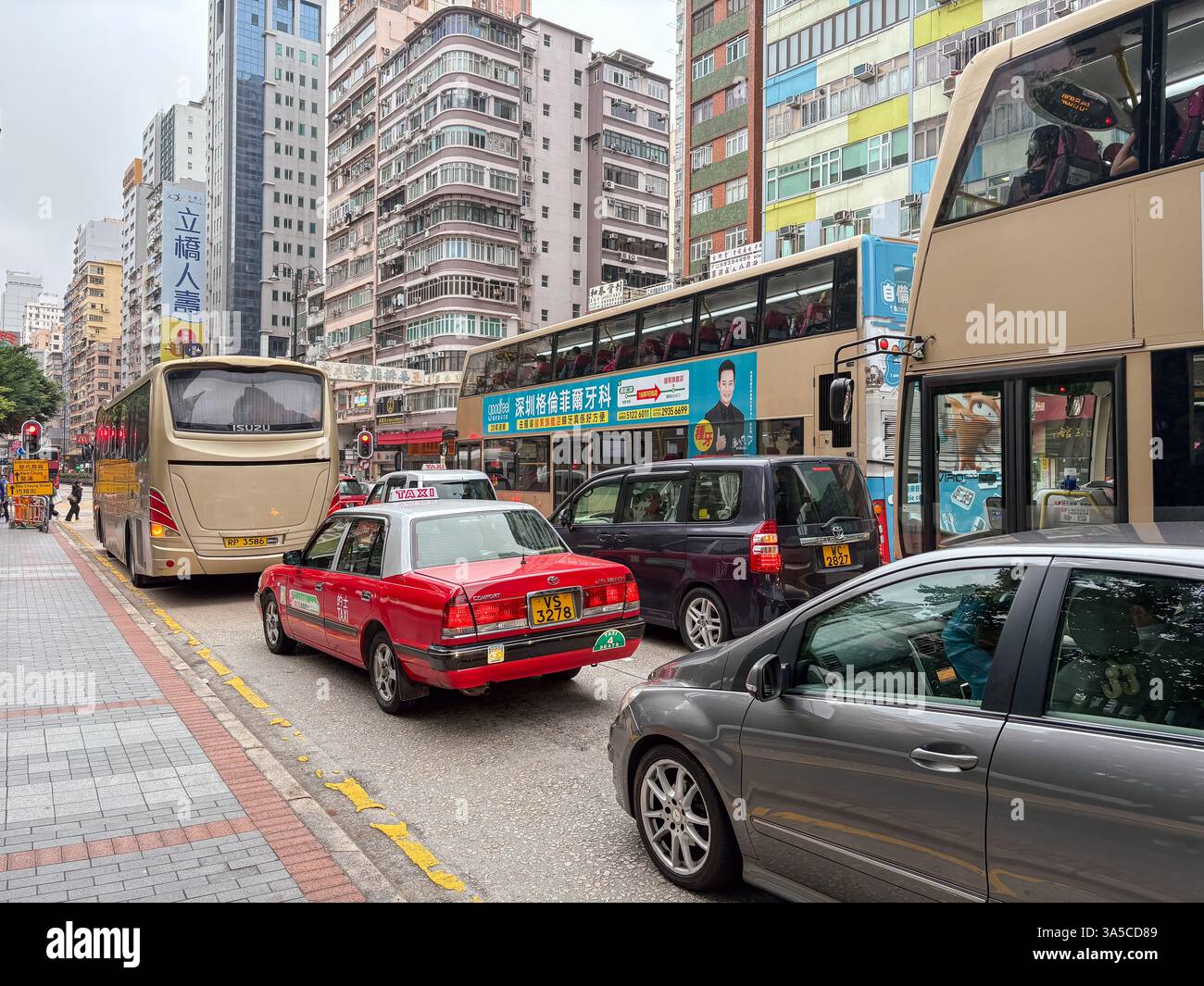 Straßenverkehr in Hongkong mit Bussen, einem Taxi und anderen Fahrzeugen in einer dichten städtischen Umgebung. Stockfoto