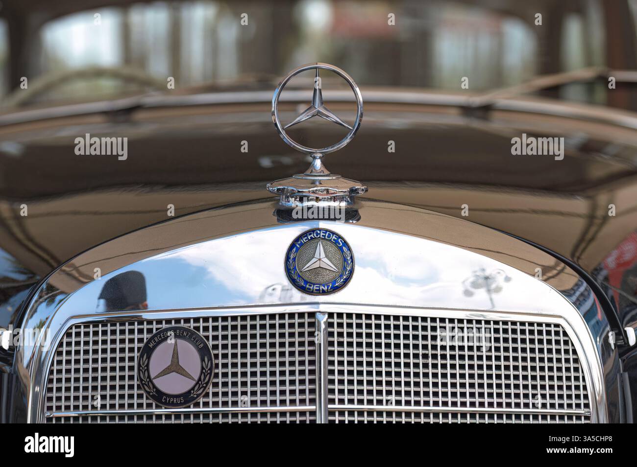 Larnaca, Zypern, 12. Mai 2024: Verchromte Kapuzenverzierung reflektiert die Wolkenlandschaft des mercedes-benz-Vintage-Modells und unterstreicht die Eleganz und Eleganz des klassischen Automobilbaus Stockfoto