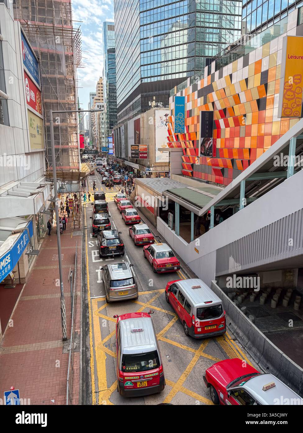 Blick auf die Mong Kok Straße mit Verkehr in Hongkong. Aus der Vogelperspektive auf eine geschäftige Straße mit Geschäften und Menschen an einem sonnigen Tag. Stockfoto
