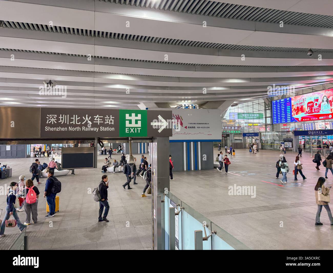 Innenansicht des Bahnhofs Shenzhen North. Umfasst das Ausstiegsschild, Pendler und digitale Anzeigetafeln. Stockfoto