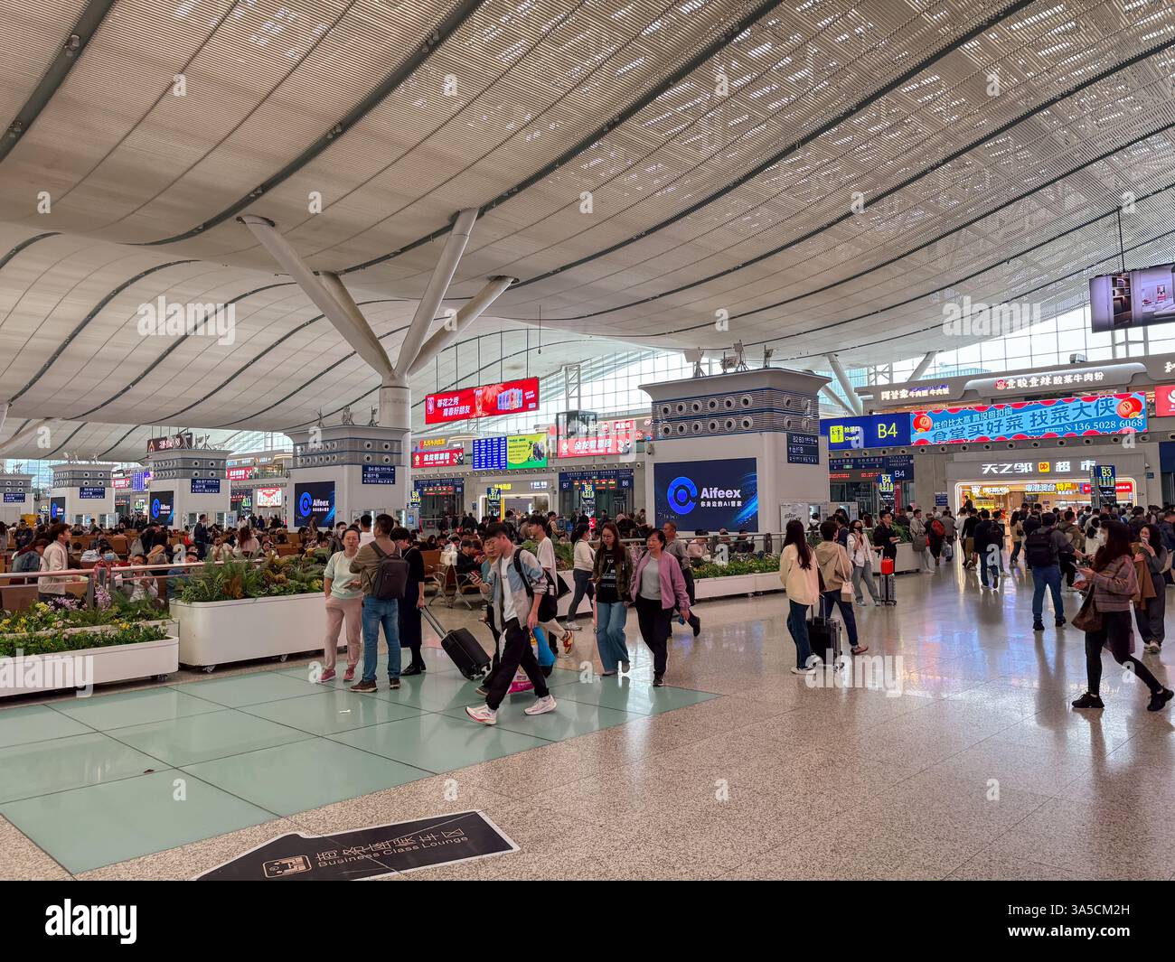 Das Innere des Shenzhen North Train Station in China mit vielen Pendlern, Geschäften und Wartebereichen. Stockfoto