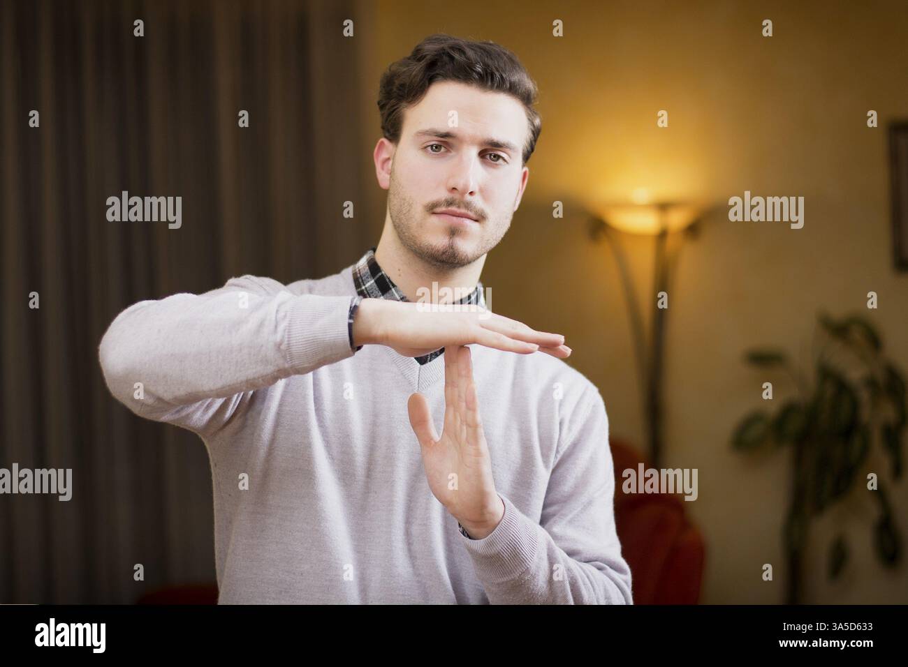 Attraktive junge Mann tut Timeout Zeichen, indoor erschossen in einem Haus Stockfoto