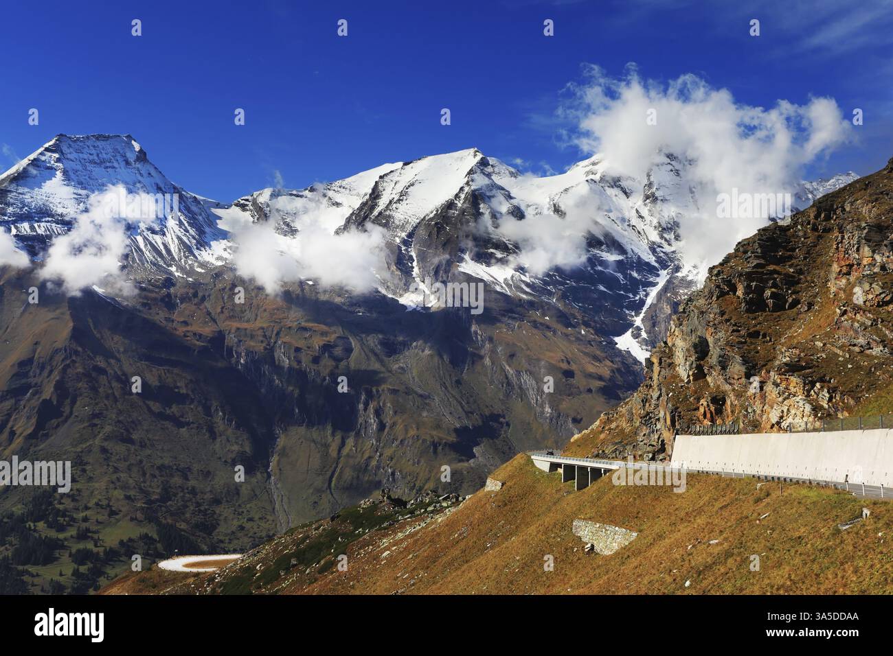 Ausflug zur malerischen Panoramastraße Großgloknershtrasse. Sonniger Tag im Frühherbst. Große Autobahnwinde zwischen den Hängen vergilbt. Österreich A Stockfoto