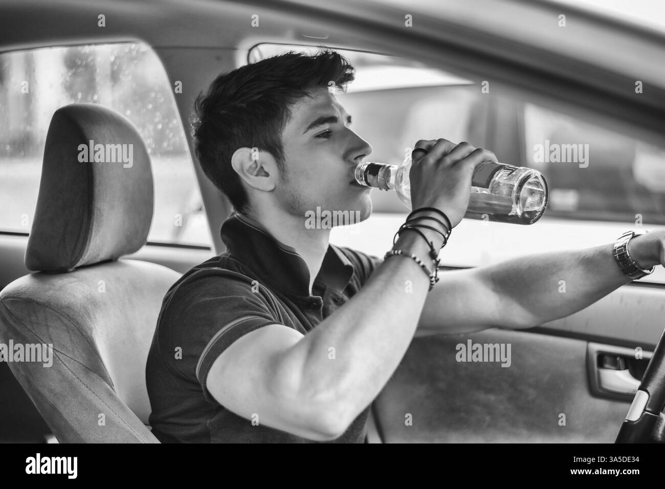 Schönen jungen Mann mit seinem Auto beim Trinken von Alkohol im Straßenverkehr. Schwarz / weiß Foto Stockfoto