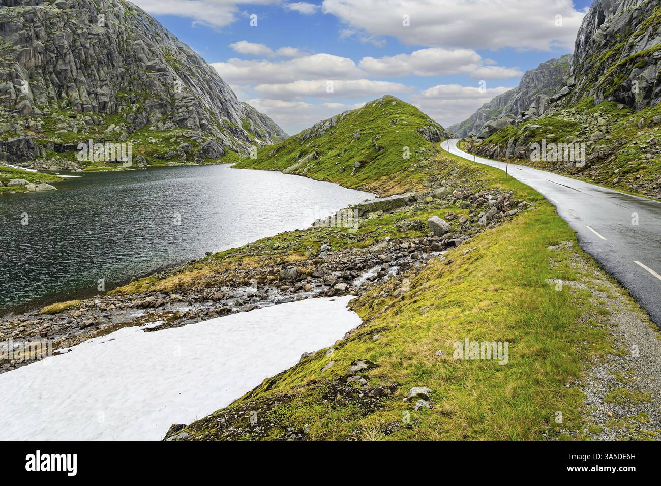 Schmale und gefährliche Bergstraße glitzert vom Regen. Fahrt mit dem Wohnmobil auf der Straße 520. Graue Felsen umgeben den See. Kalter Sommer in Norwegen Stockfoto