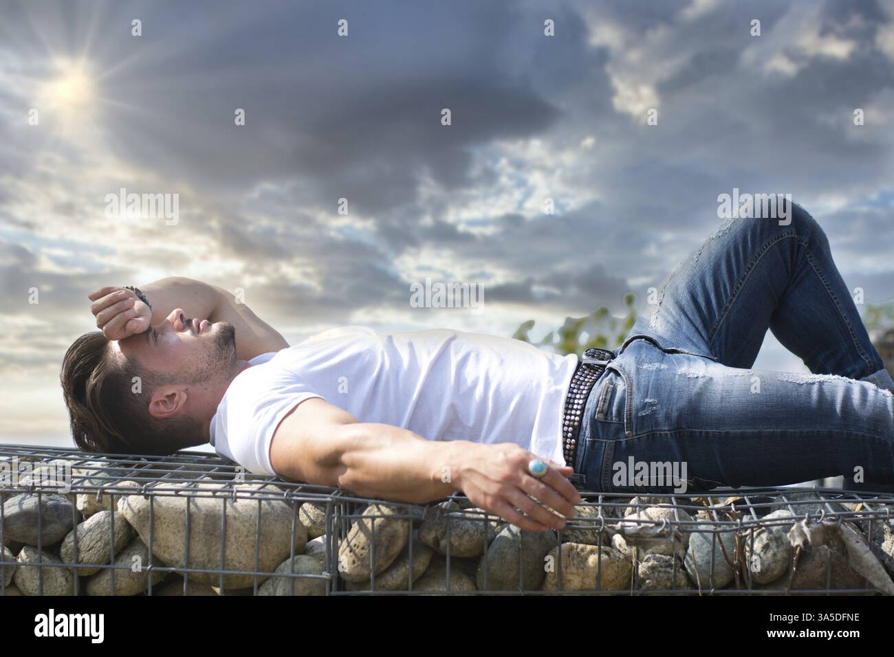 Hübscher junger Mann, der auf Steinblöcken liegt und die Augen geschlossen hat Stockfoto