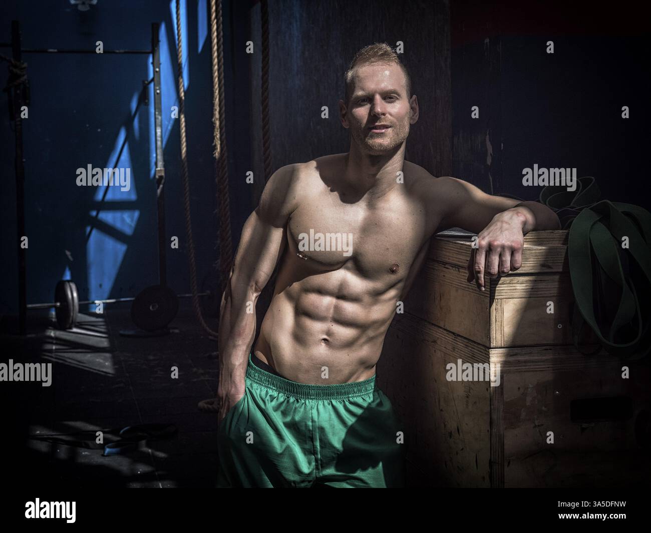 Schöner muskulöser junger Mann, der während des Trainings im Fitnessstudio steht und in die Kamera blickt Stockfoto