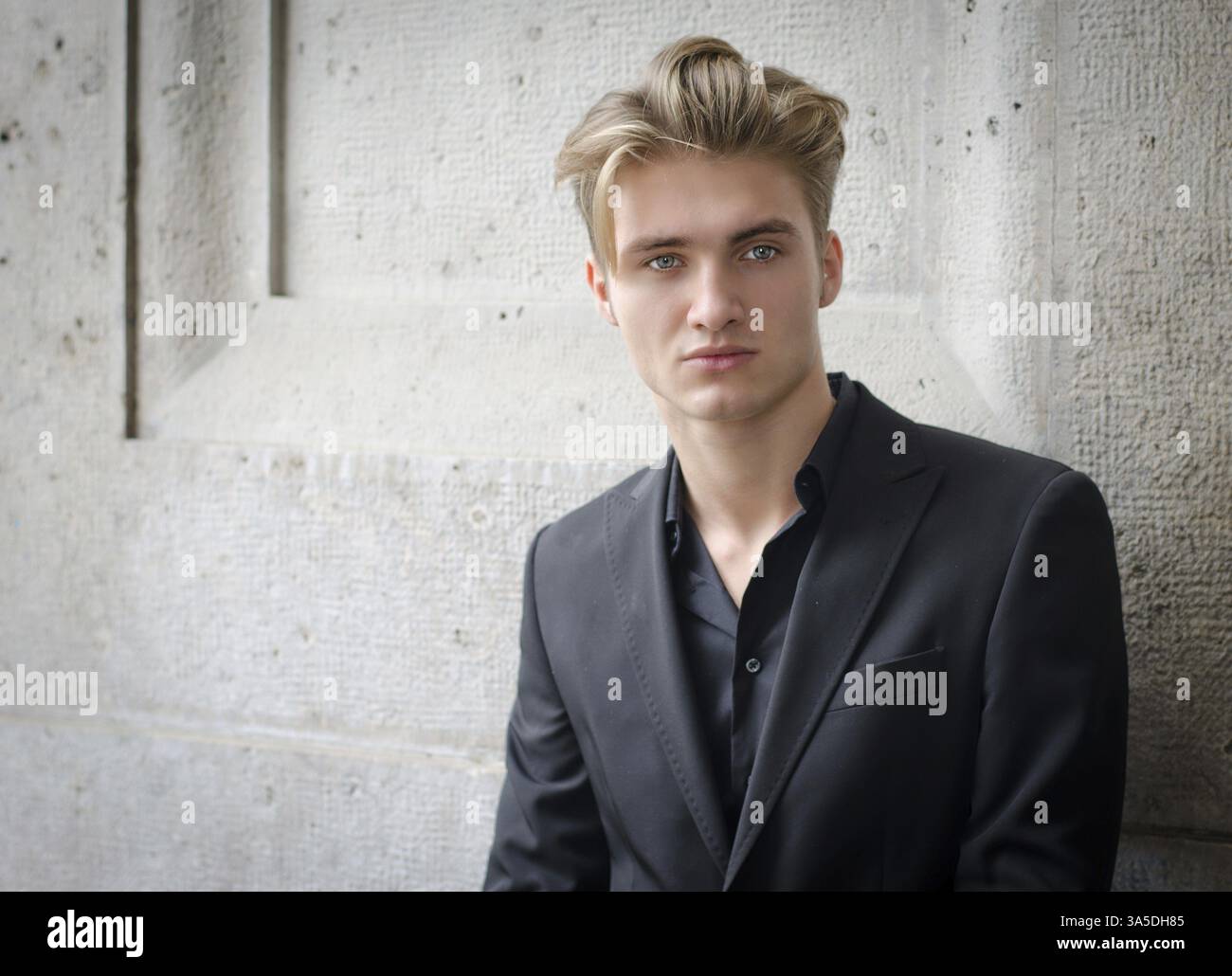 Attraktive blonde Jüngling in Hemd und Jacke, gegen Wand Stockfoto