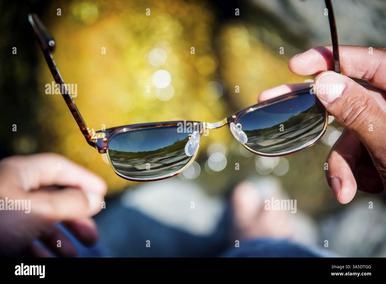 Nicht erkennbare Mann Betrieb Sonnenbrille. Von oben. Bokeh Stockfoto