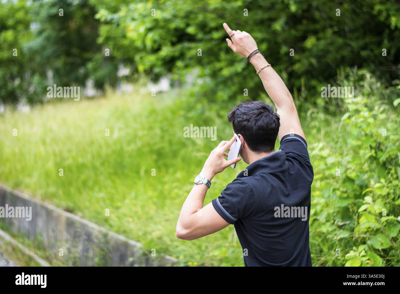 Schönen jungen Mann auf einer Straßenseite anrufen auf Handy und warten für Taxi Taxi Stockfoto