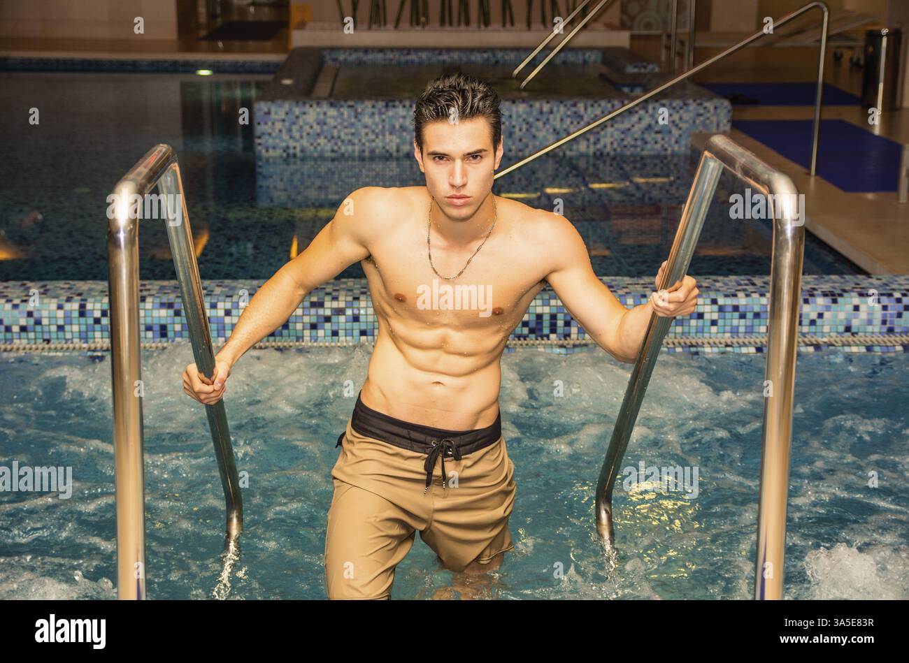 Gutaussehender athletischer junger Mann, der sich im Spa-Whirlpool in ruhiger Umgebung entspannt Stockfoto