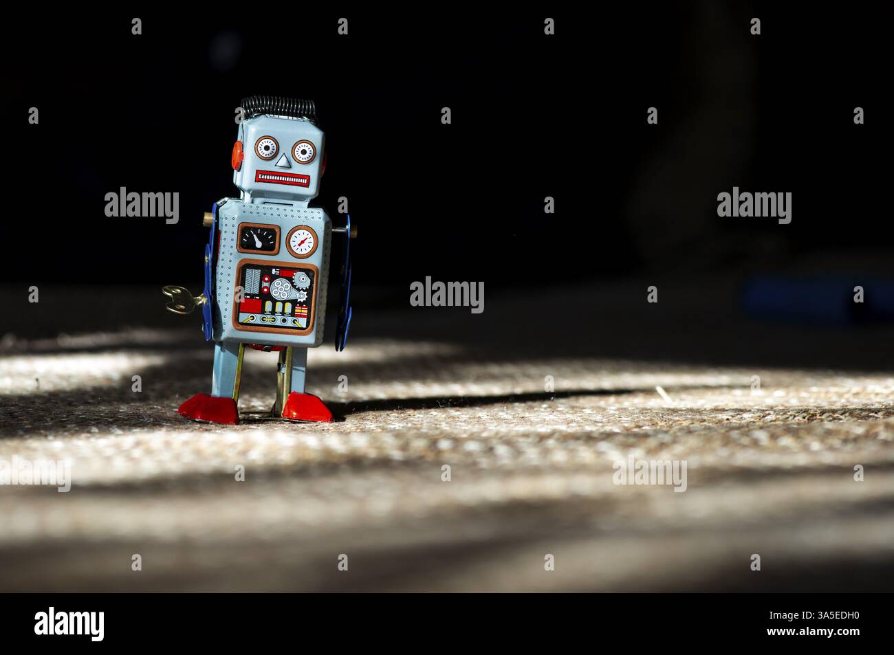 Vintage Metall blau Roboter Spielzeug auf Sonneneinstrahlung. Futuristisches Konzept mit kleinen mechanischen Roboter Spielzeug zu Fuß auf Tuch Oberfläche. Gemalte Augen und elektronischen das Stockfoto