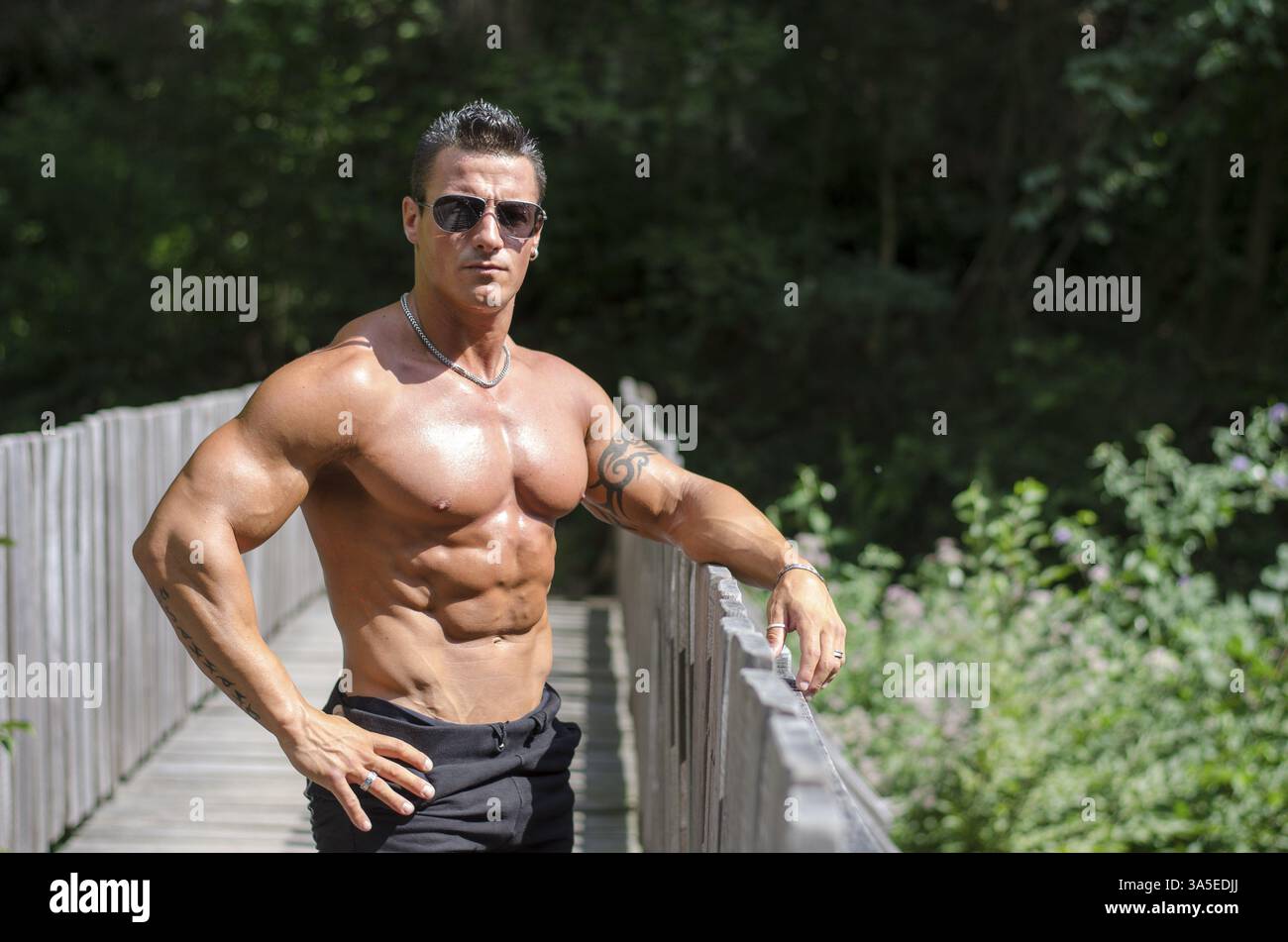 Attraktive junge Muskelprotz im Freien, stützte sich auf Metall Handläufe Stockfoto