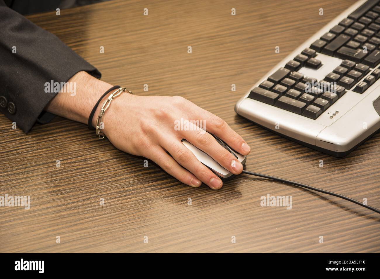 Hand eines Mannes, die Arbeit am Computer Maus in seinem Büro auf dunklen Desktop anklicken Stockfoto
