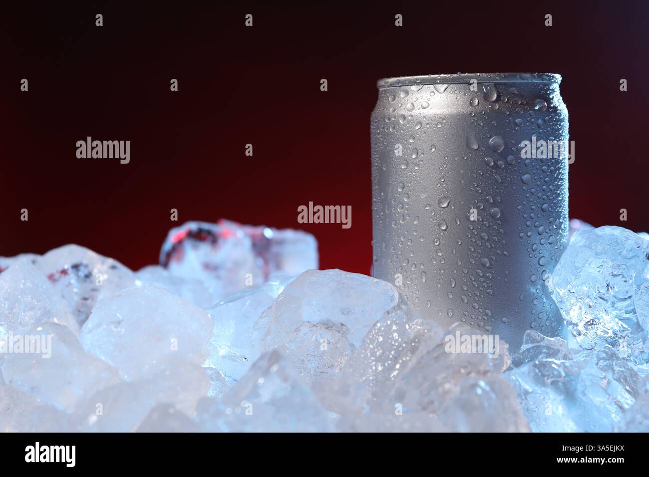 Erfrischendes Getränk in der Dose auf Eiswürfeln vor dunkelrotem Hintergrund, Nahaufnahme Stockfoto