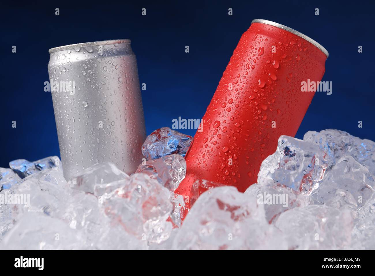 Erfrischende Getränke in Dosen auf Eiswürfeln vor dunkelblauem Hintergrund, Nahaufnahme Stockfoto