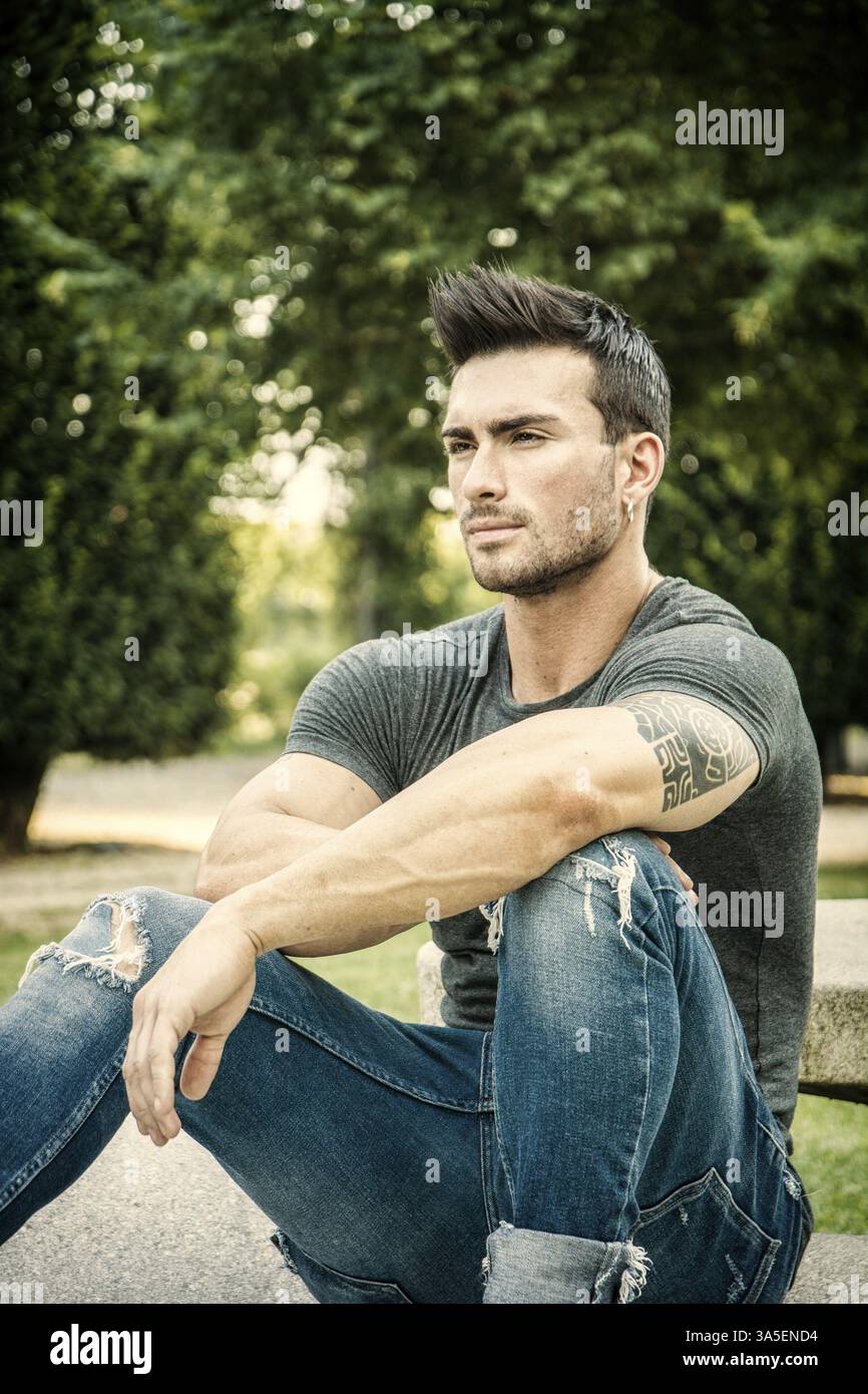 Schöner muskulöser Mann mit Tätowierung posiert im europäischen Luxusgarten in Turin, Italien, Europa Stockfoto